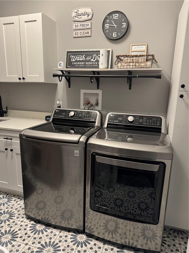 clothes washing area with separate washer and dryer, cabinet space, and light tile patterned floors