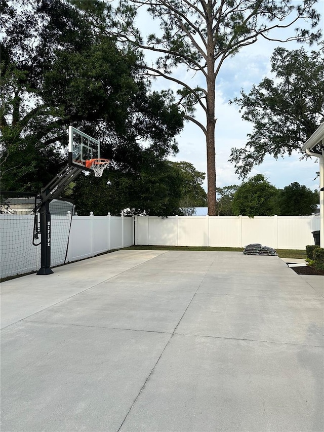 view of sport court featuring basketball hoop and fence