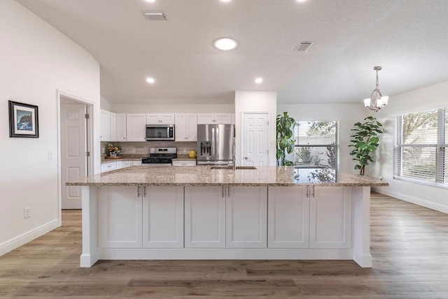 kitchen featuring appliances with stainless steel finishes, a spacious island, baseboards, white cabinetry, and a wealth of natural light