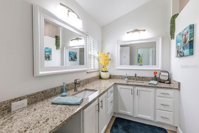 bathroom with a sink, double vanity, and lofted ceiling