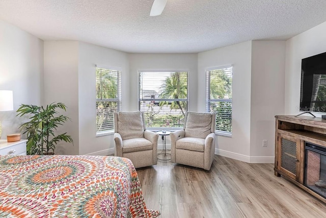 bedroom featuring a textured ceiling, multiple windows, and light wood finished floors