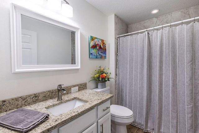 bathroom featuring vanity, a shower with curtain, toilet, and a textured ceiling