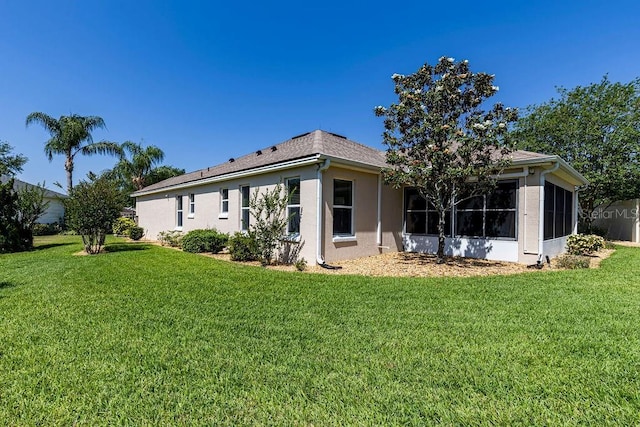 back of house featuring a yard, stucco siding, and a sunroom