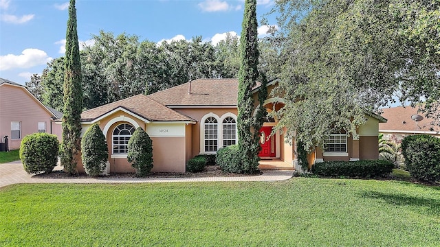 mediterranean / spanish home featuring roof with shingles, stucco siding, and a front lawn