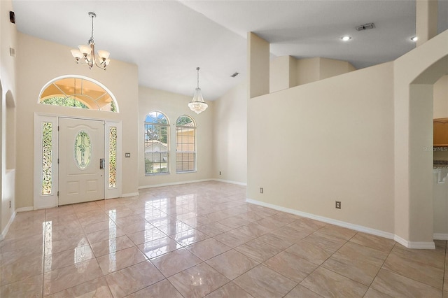 entryway featuring baseboards, arched walkways, high vaulted ceiling, and a notable chandelier