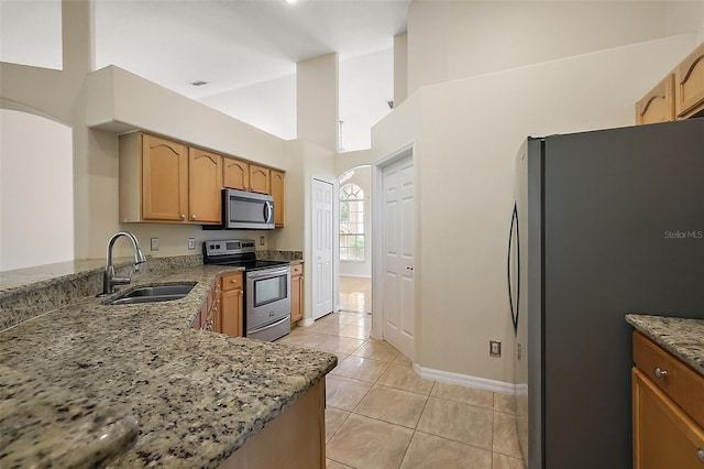 kitchen with light stone countertops, light tile patterned floors, baseboards, a sink, and stainless steel appliances
