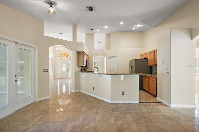 kitchen featuring light tile patterned floors, a breakfast bar, visible vents, a peninsula, and arched walkways
