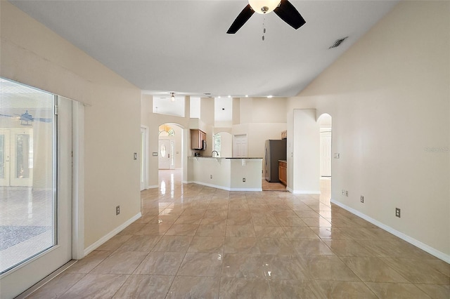 unfurnished living room with arched walkways, ceiling fan, baseboards, and visible vents