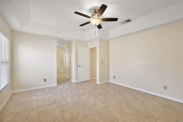 spare room featuring a ceiling fan, a raised ceiling, baseboards, and visible vents