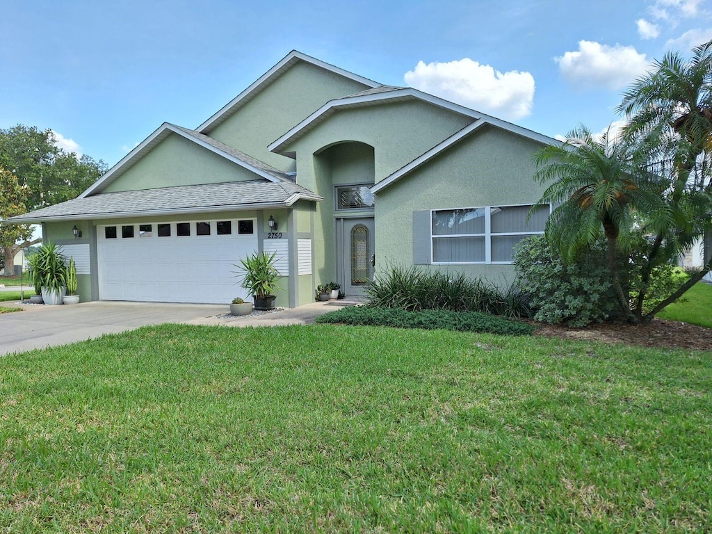 2750 Coral Reef Way, Tavares, FL 32778 - view of front facade featuring a garage, stucco siding, a front lawn, and driveway