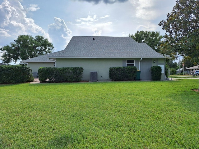 2750 Coral Reef Way, Tavares, FL 32778 - view of side of property with a lawn, central AC, stucco siding, and a shingled roof