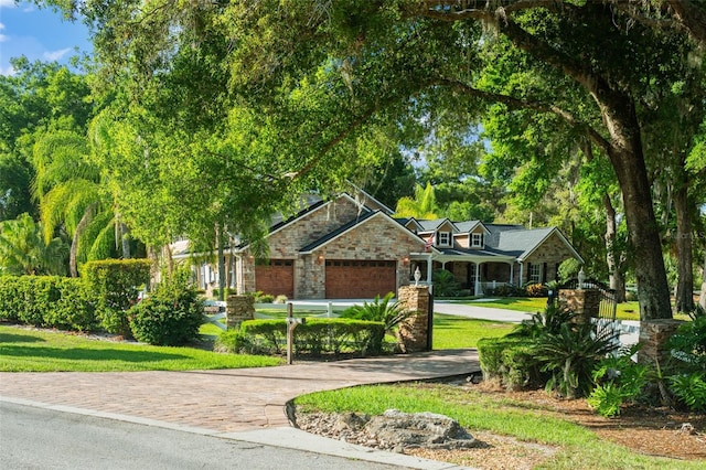 craftsman inspired home with an attached garage, a front lawn, stone siding, and concrete driveway