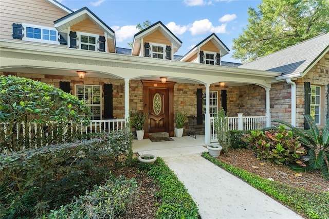 view of exterior entry featuring covered porch and stone siding