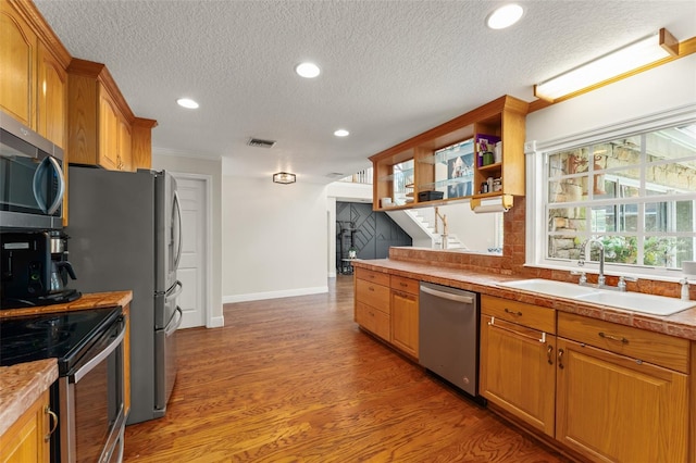 kitchen with a sink, light wood finished floors, a textured ceiling, stainless steel appliances, and visible vents