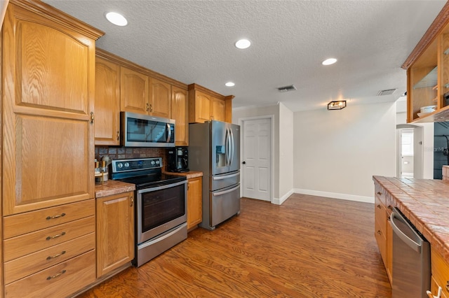 kitchen featuring appliances with stainless steel finishes, tile counters, baseboards, and visible vents
