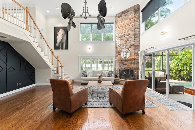 living area with stairs, a high ceiling, wood finished floors, and a fireplace