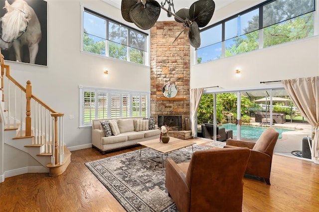 living area with baseboards, a towering ceiling, wood finished floors, and a healthy amount of sunlight
