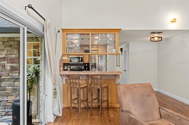 bar with baseboards, appliances with stainless steel finishes, wood finished floors, and visible vents