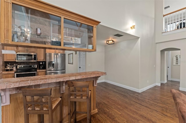 kitchen with visible vents, arched walkways, appliances with stainless steel finishes, and dark wood-style floors
