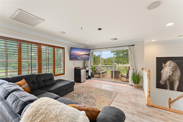 living area with visible vents, ornamental molding, baseboards, and wood finished floors