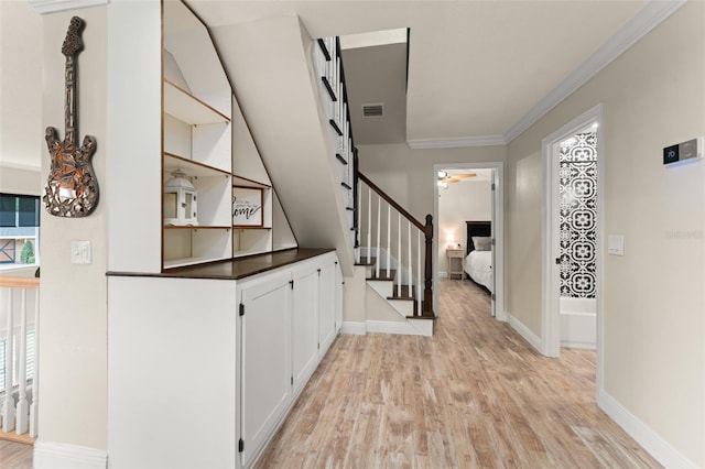 corridor featuring visible vents, ornamental molding, stairs, light wood-style floors, and baseboards