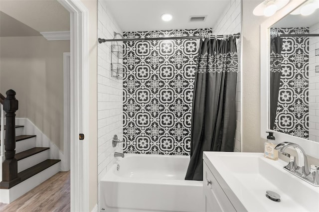 full bathroom with visible vents, crown molding, wood finished floors, shower / tub combo, and vanity