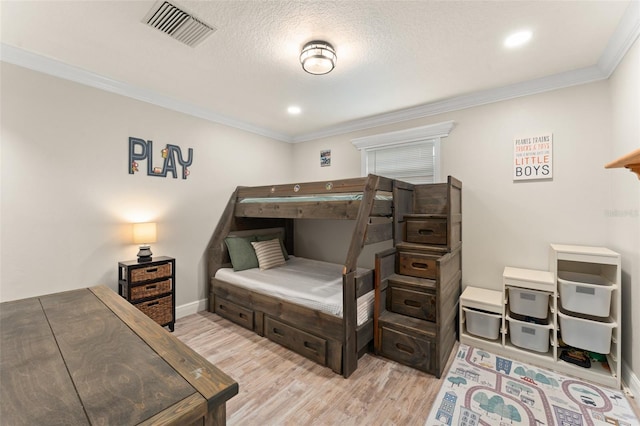 bedroom with crown molding, baseboards, light wood finished floors, and visible vents