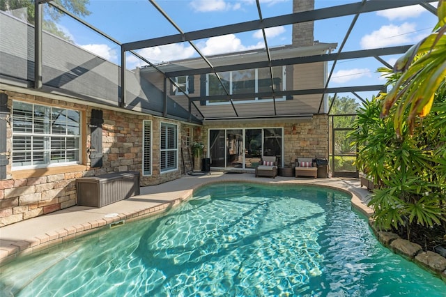outdoor pool featuring glass enclosure, outdoor lounge area, and a patio area