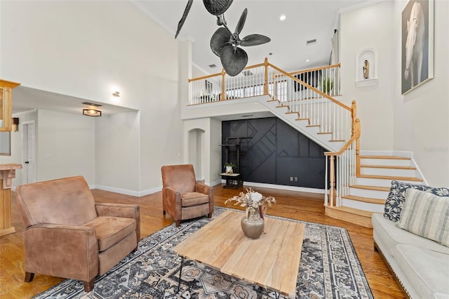 living room with a ceiling fan, crown molding, wood finished floors, baseboards, and stairs