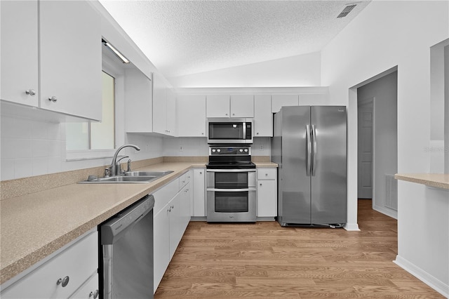 kitchen featuring stainless steel appliances, a textured ceiling, white cabinetry, and a sink