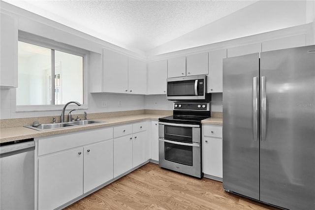 kitchen with a sink, a textured ceiling, appliances with stainless steel finishes, and light countertops