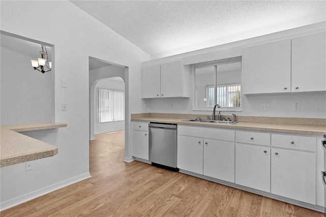 kitchen featuring light wood-style floors, light countertops, arched walkways, a sink, and dishwasher