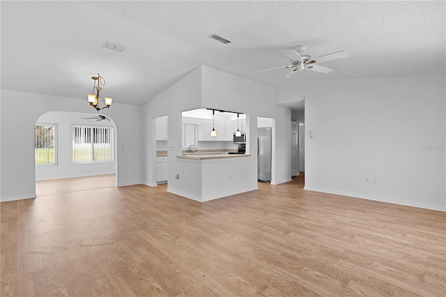 unfurnished living room featuring light wood-style floors, arched walkways, ceiling fan with notable chandelier, and visible vents