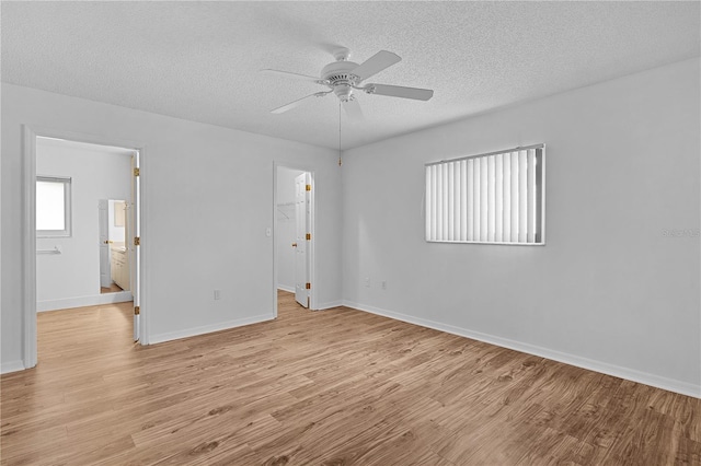 spare room with light wood-style floors, a textured ceiling, ceiling fan, and baseboards