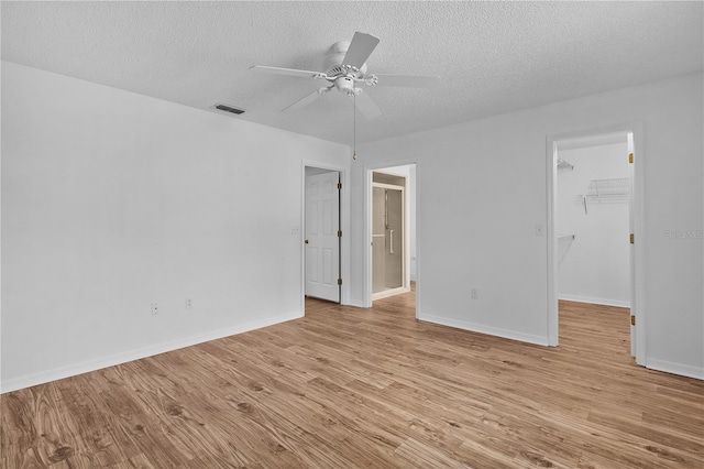 spare room with ceiling fan, a textured ceiling, visible vents, baseboards, and light wood finished floors