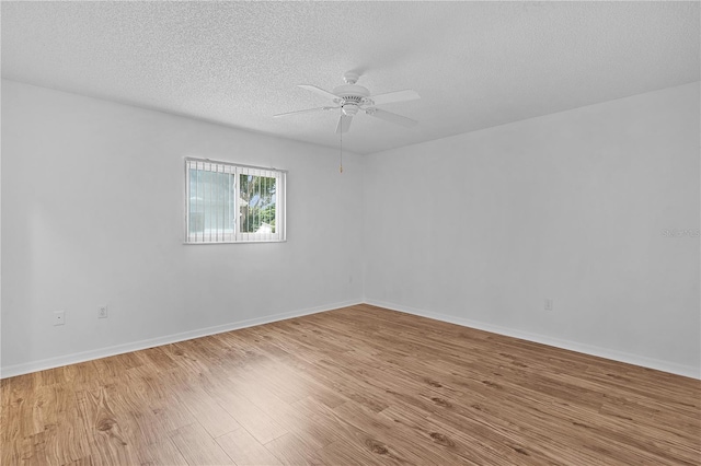 empty room with baseboards, a textured ceiling, ceiling fan, and wood finished floors