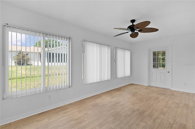 empty room featuring a ceiling fan, baseboards, a textured ceiling, and light wood-type flooring