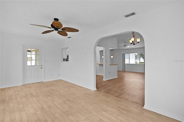 unfurnished room with visible vents, arched walkways, baseboards, ceiling fan with notable chandelier, and light wood-style floors