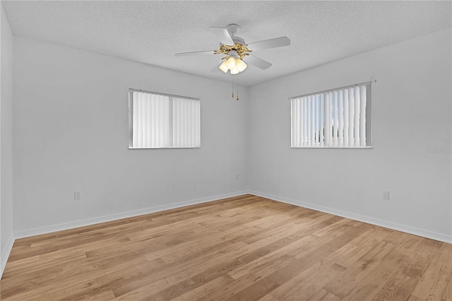 spare room with baseboards, a textured ceiling, ceiling fan, and light wood-style flooring