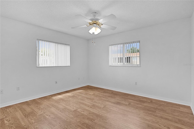 empty room with light wood-type flooring, a textured ceiling, ceiling fan, and baseboards
