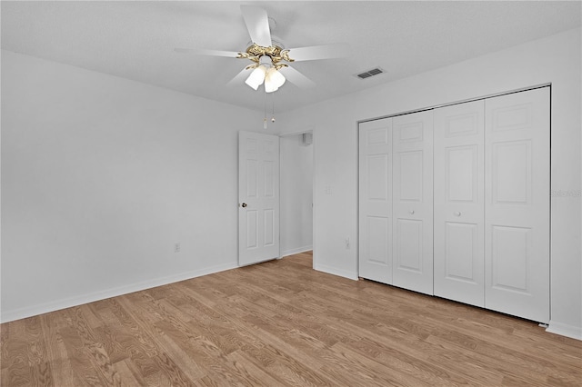 unfurnished bedroom featuring visible vents, light wood-style floors, baseboards, and a closet