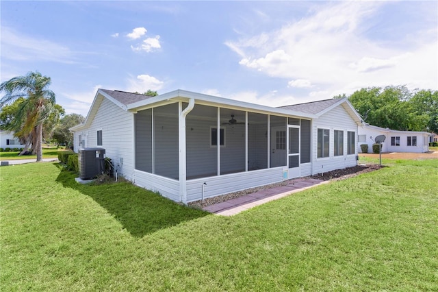 rear view of property featuring central air condition unit, a lawn, a ceiling fan, and a sunroom