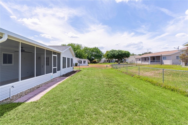 view of yard with fence, a ceiling fan, and a sunroom