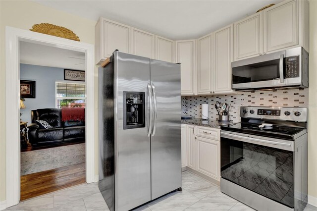 506 Richard St, Leesburg, FL 34748 - kitchen featuring stainless steel appliances, light marble finish flooring, cream cabinetry, and backsplash
