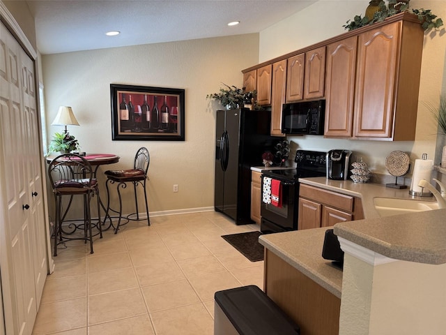 1288 Grady Ln, Davenport, FL 33896 - kitchen with black appliances, light tile patterned floors, recessed lighting, and brown cabinets