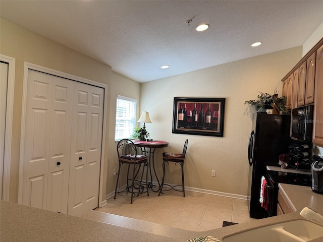 1288 Grady Ln, Davenport, FL 33896 - kitchen featuring black appliances, a textured ceiling, light tile patterned floors, recessed lighting, and light countertops