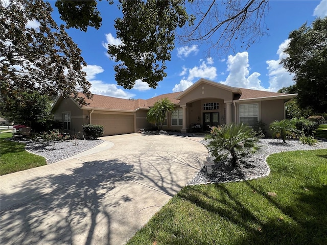 single story home featuring french doors, a front yard, a garage, concrete driveway, and stucco siding