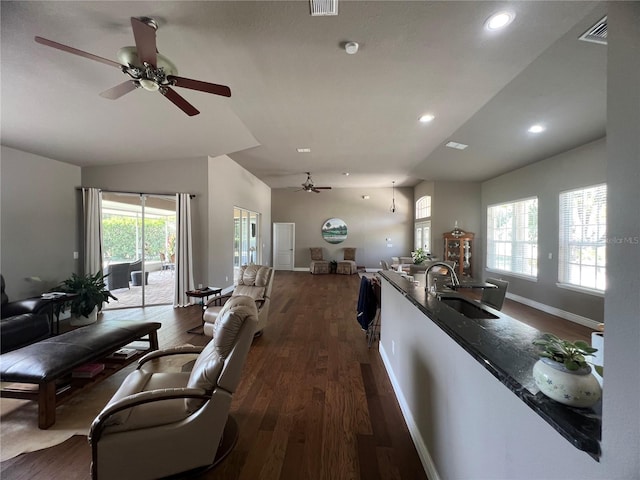 living room featuring visible vents, dark wood-style flooring, lofted ceiling, baseboards, and a ceiling fan