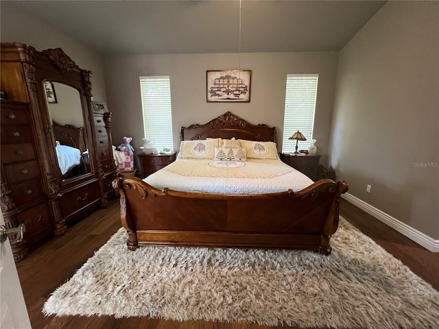 bedroom featuring baseboards, multiple windows, and dark wood finished floors