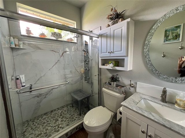 bathroom with a marble finish shower, vanity, and toilet